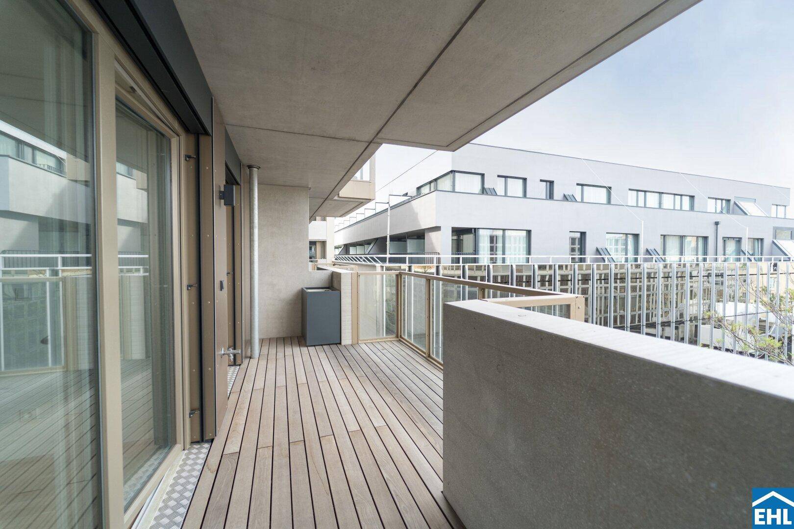 Geräumiger Balkon mit Holzdeck und Blick auf moderne Architektur der Umgebung.