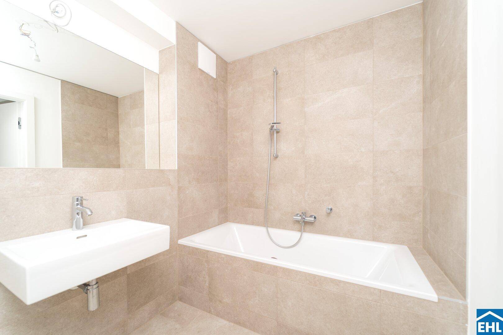Modernes Badezimmer mit beigefarbenen Fliesen, einer Badewanne und einem eleganten Waschbecken.