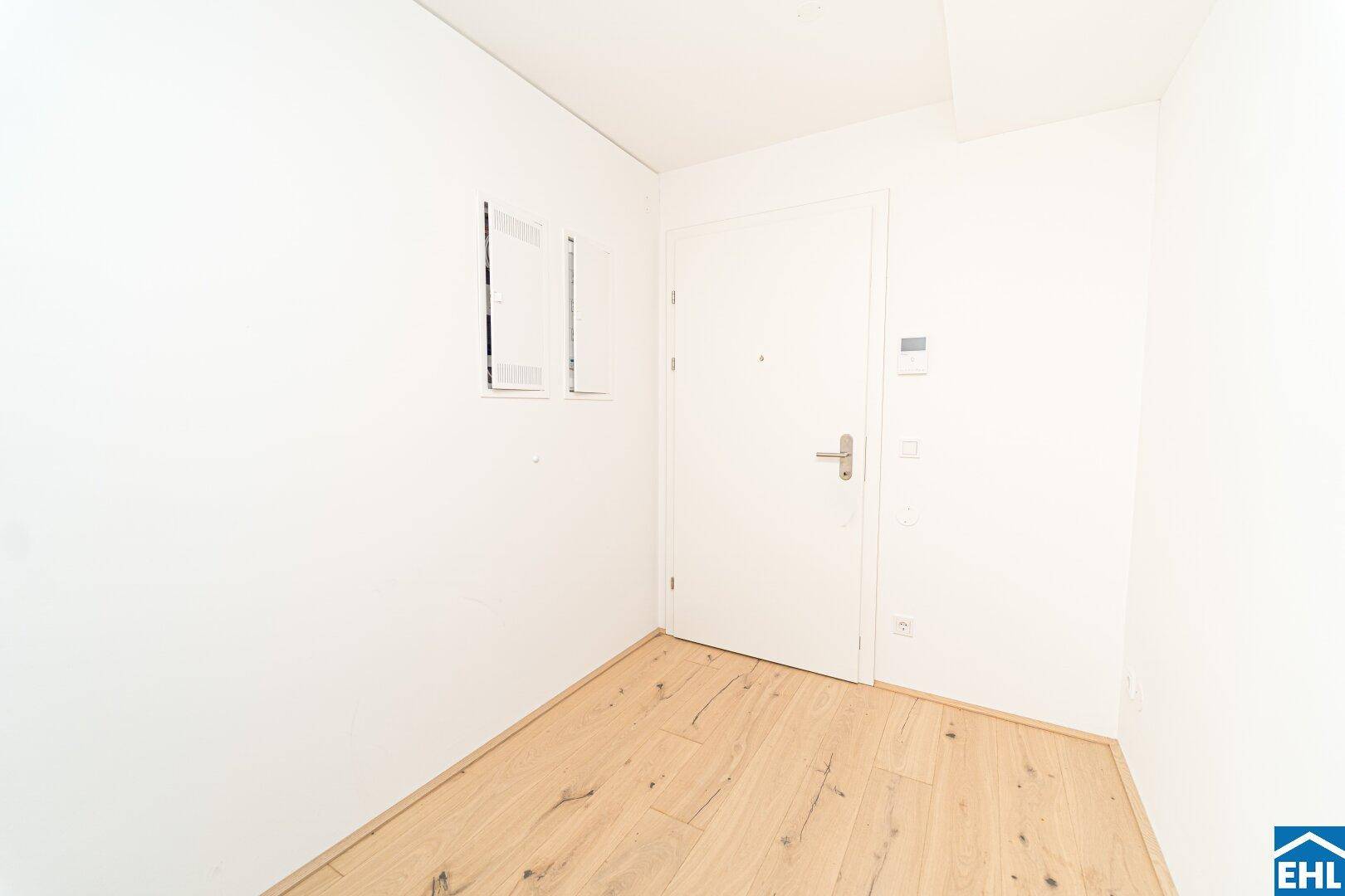 Heller Eingangsbereich mit Holzboden und weißer Tür, der einen sauberen ersten Eindruck vermittelt.