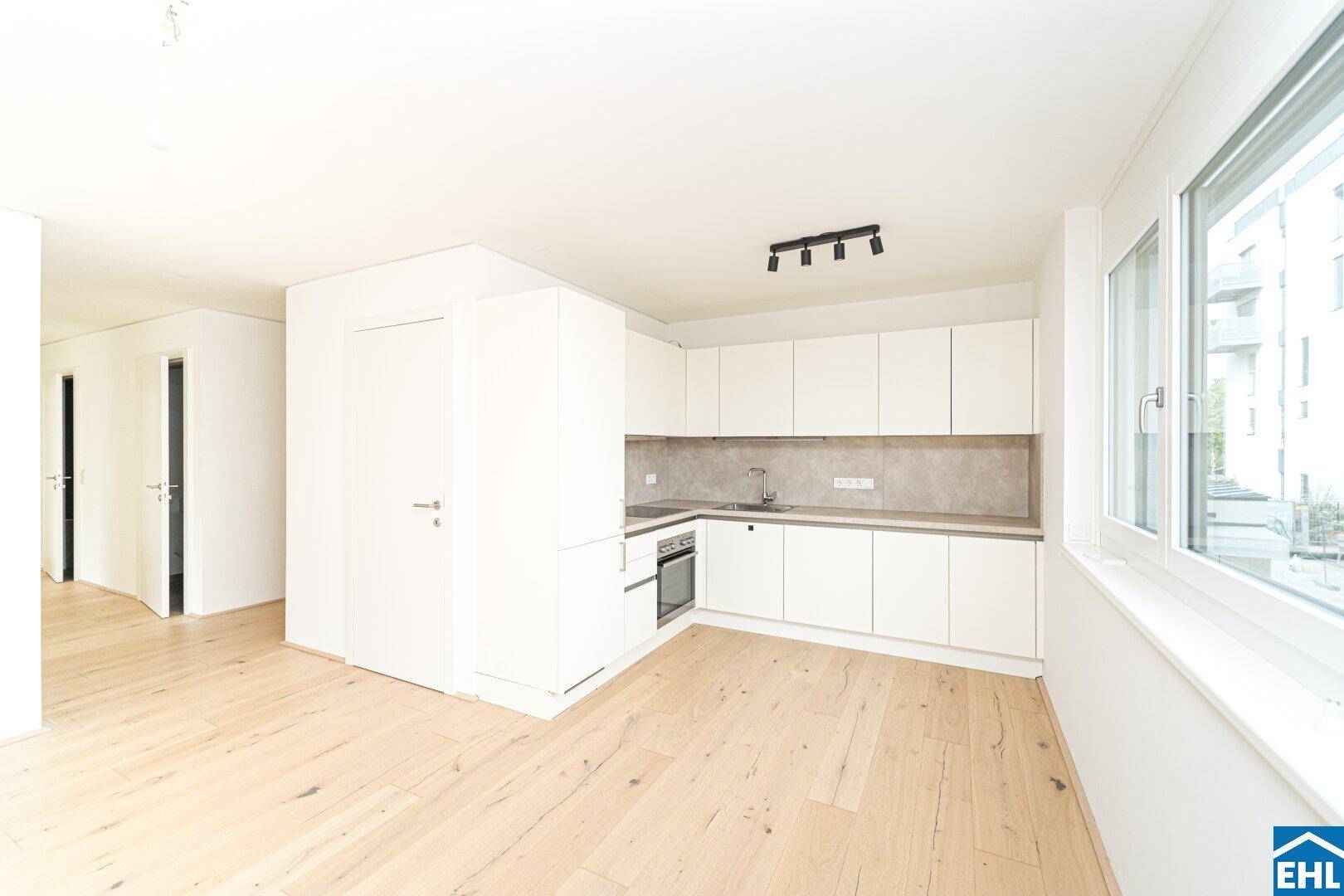 Moderne Einbauküche mit weißen Schränken, integrierten Geräten und Fenster.
