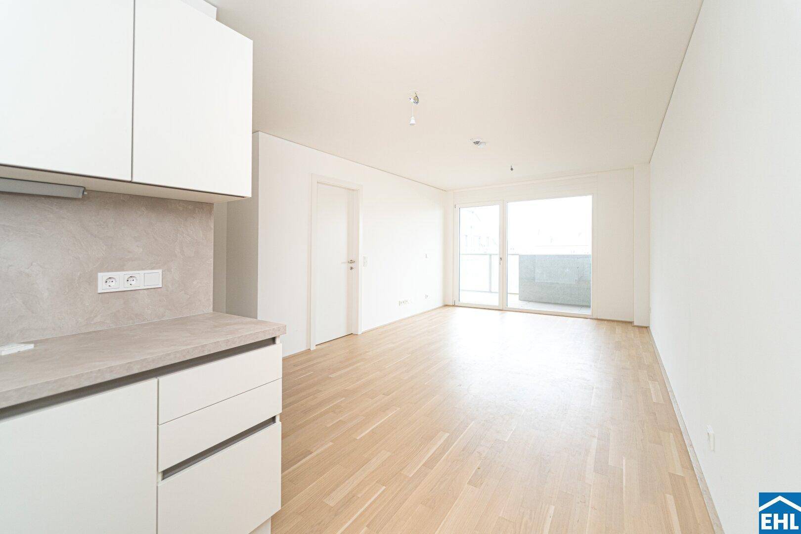 Heller Wohnbereich mit Parkettboden und Zugang zu einem Balkon, ideal für entspannte Stunden.