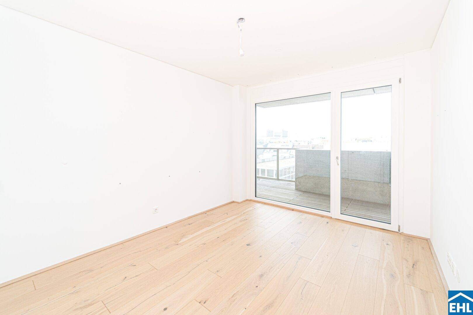 Helles Zimmer mit Holzboden und direktem Zugang zu einem Balkon, ideal als Schlafzimmer.