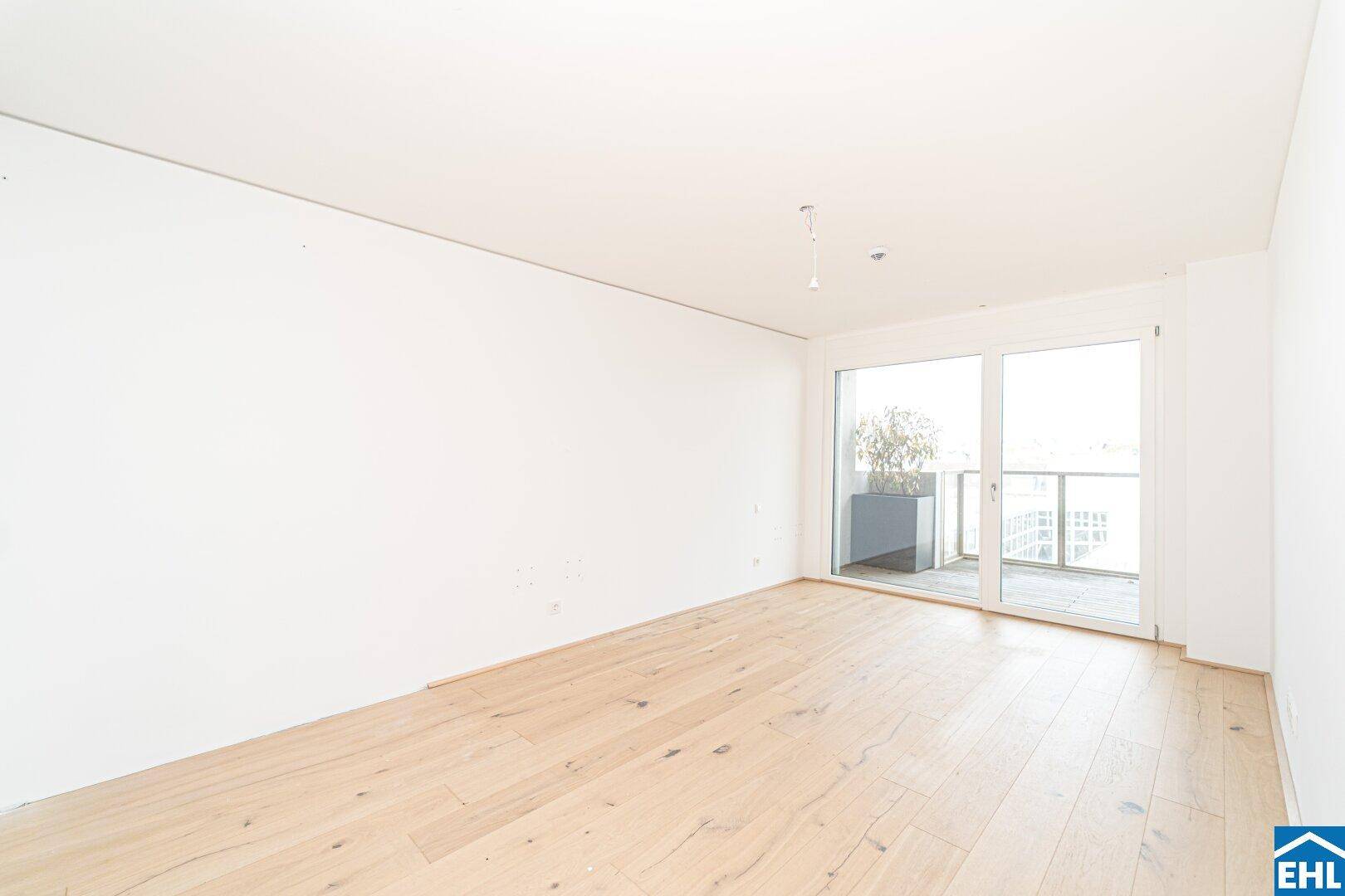 Geräumiges Zimmer mit Holzboden und Balkonzugang, bietet viel natürliches Licht.