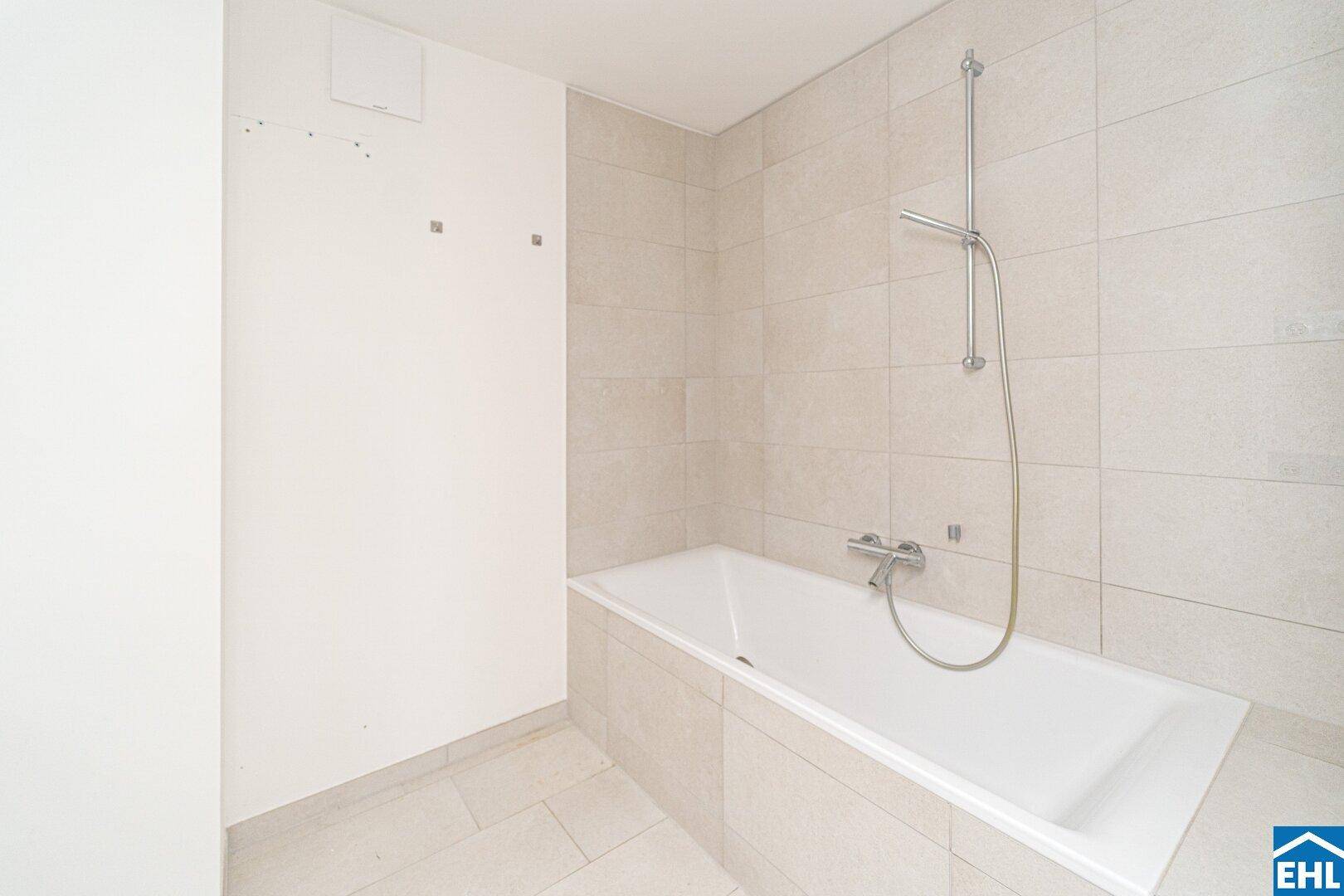 Modernes Badezimmer mit heller Fliesenverkleidung und einer Badewanne mit Duschfunktion.
