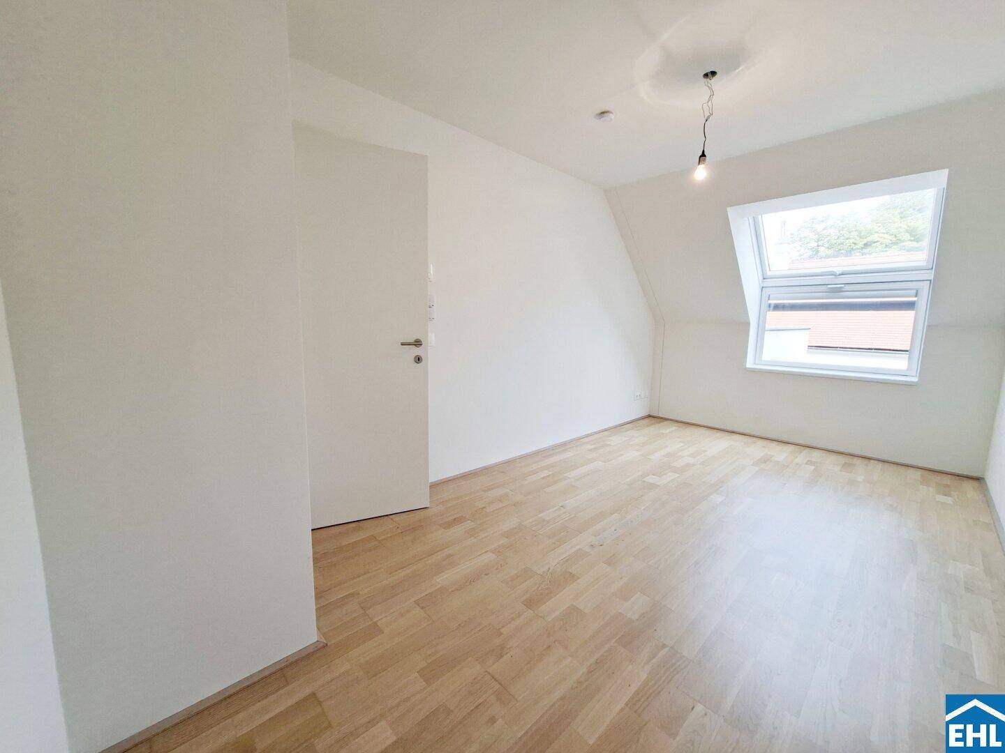 Gemütliches Schlafzimmer mit Holzboden, Dachschräge und einem großen Dachfenster für viel Licht.