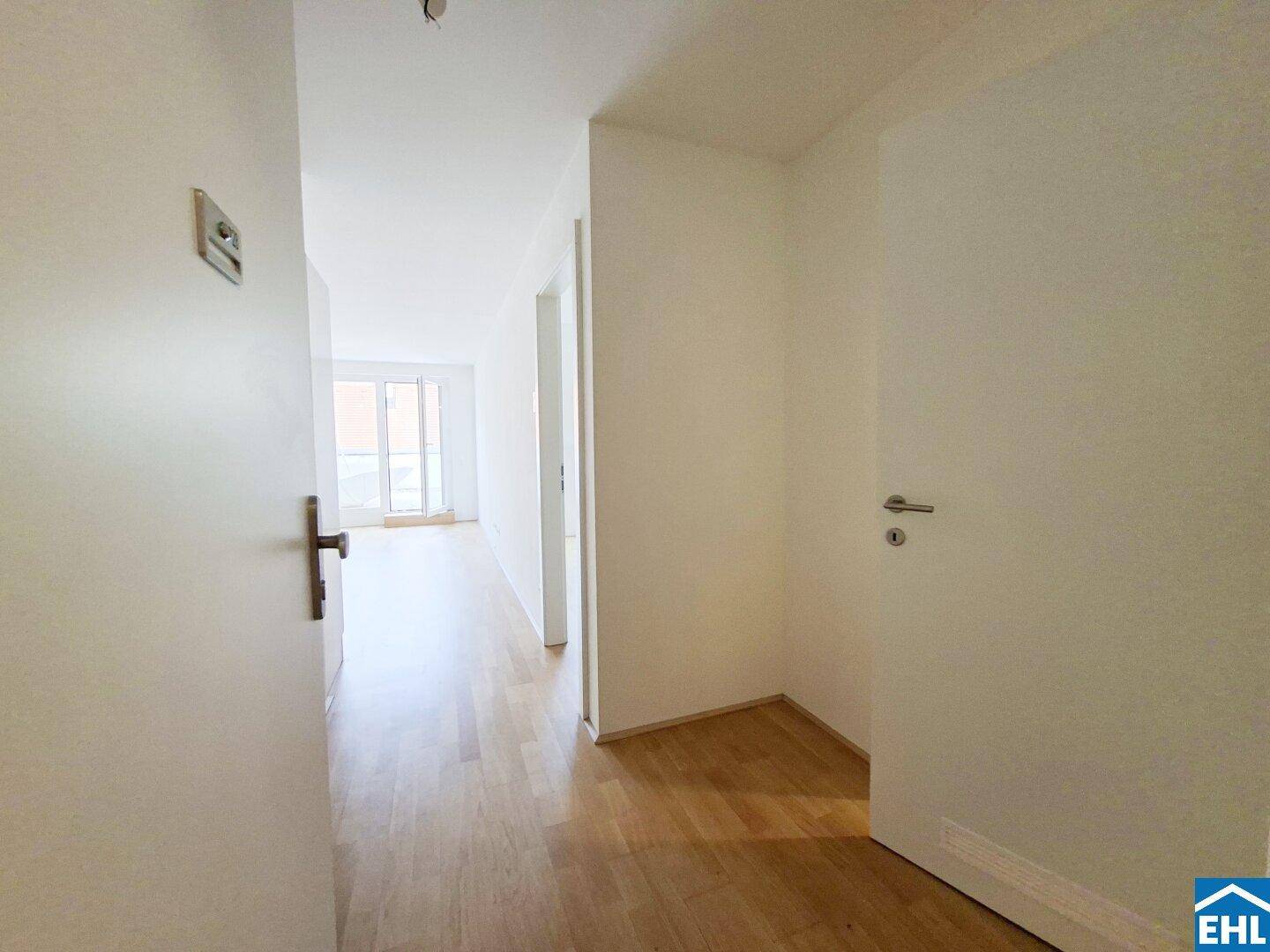 Heller Flur mit Holzboden, der zu weiteren Räumen und einem hellen Bereich führt.
