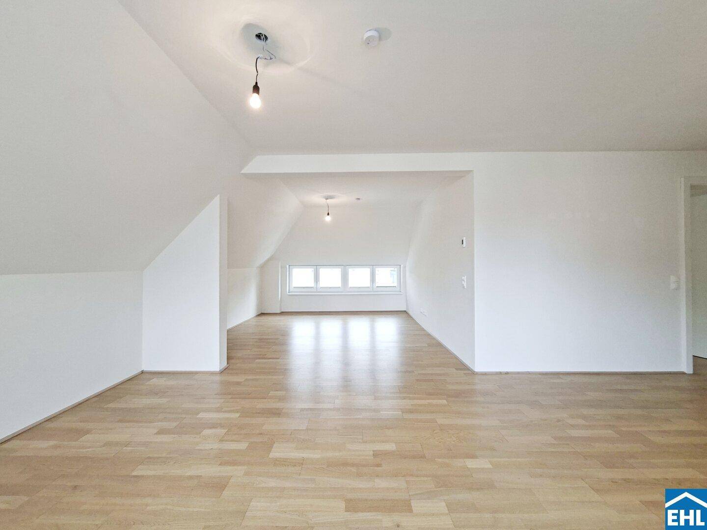 Heller und geräumiger Wohnbereich mit Dachschrägen und großen Fenstern.