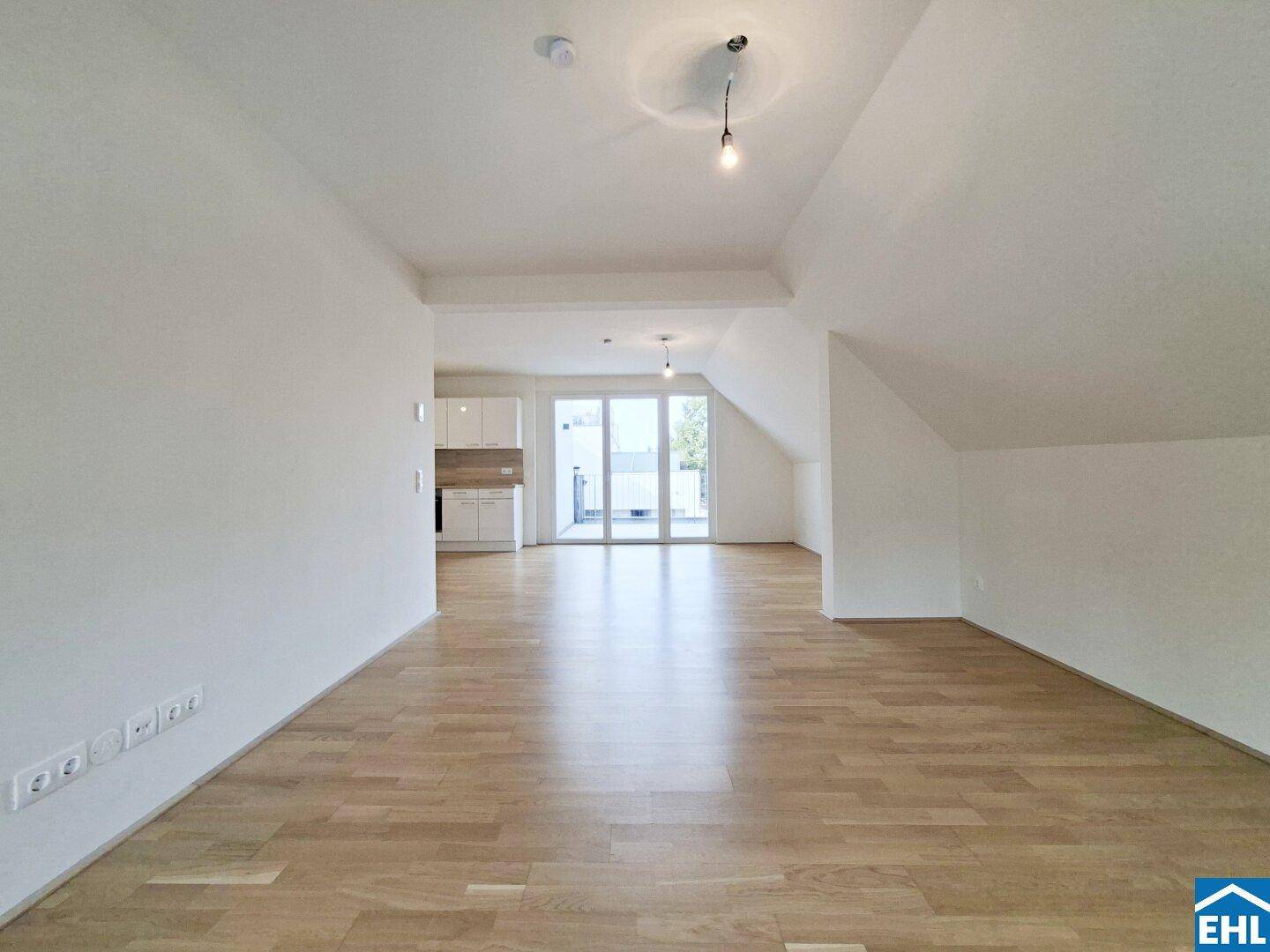 Offener Wohnbereich mit Holzfußboden und Blick auf die moderne Küche.