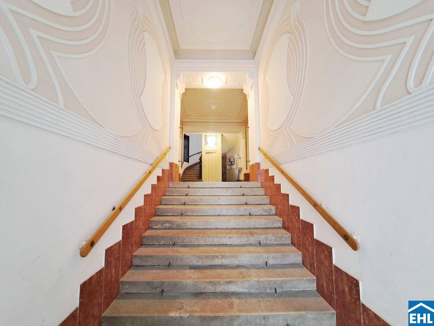 Repräsentatives Treppenhaus in einem Altbau mit kunstvollen Stuckverzierungen und Steinstufen.