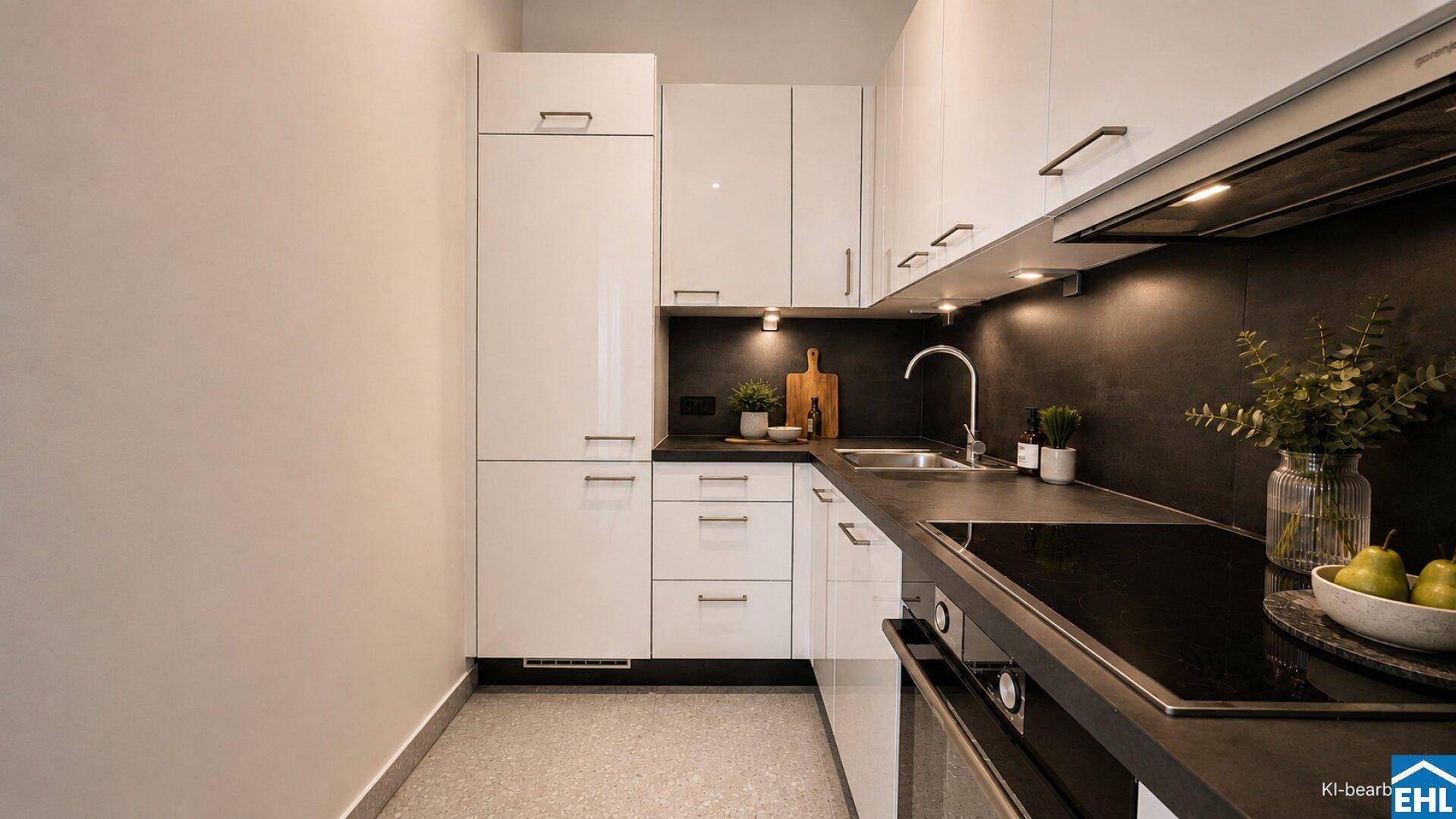 Moderne Küche mit weißen Hochglanzschränken, dunkler Arbeitsplatte und integrierten Geräten.