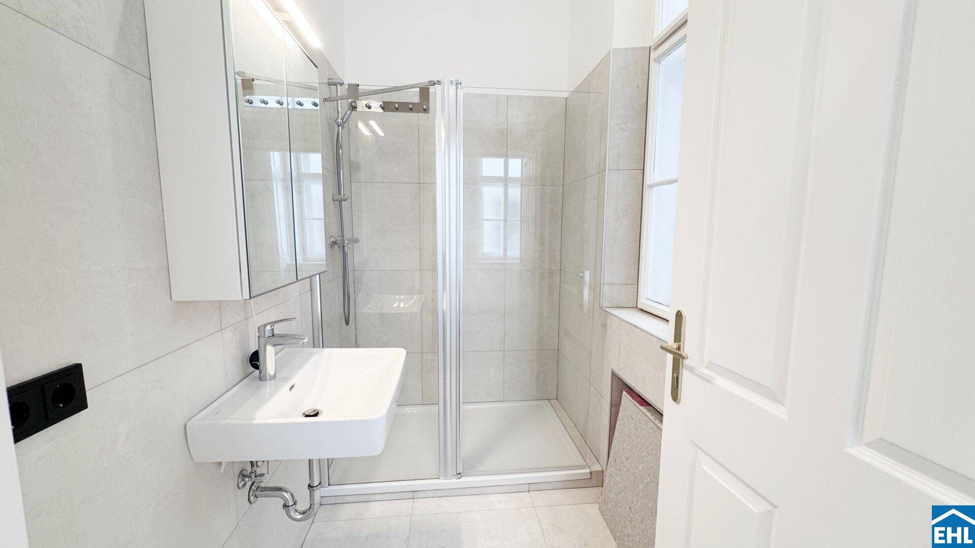 Helles, modernes Badezimmer mit Duschkabine, Einzelwaschbecken und Fenster, bereit zur Nutzung.