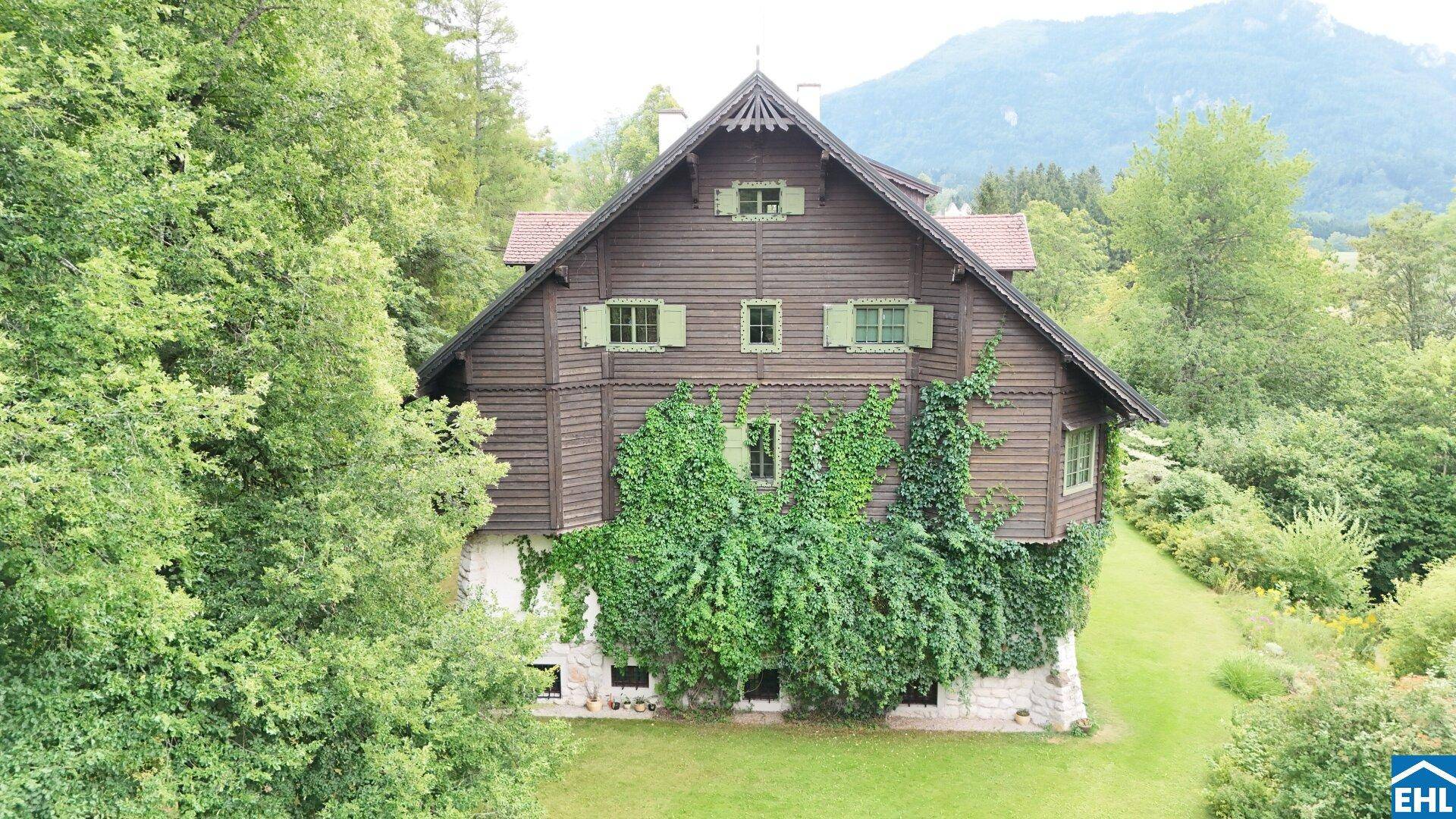 Rustikale Holzfassade des Hauses mit üppigem Efeu und traditionellen grünen Fensterläden.
