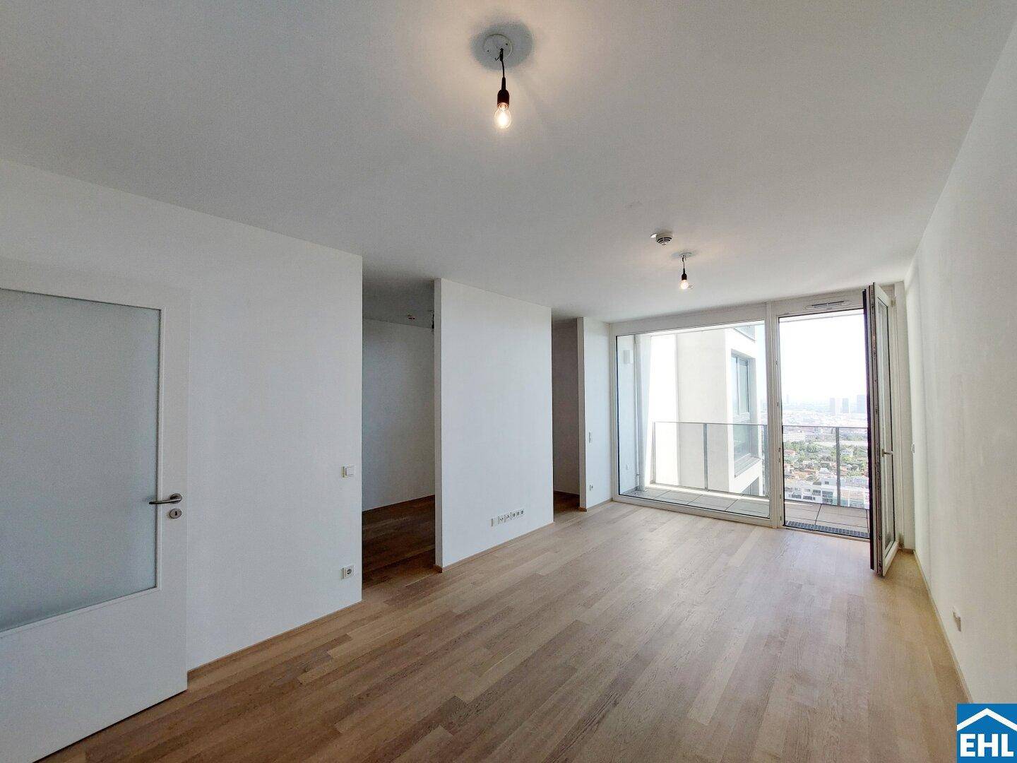 Helles, leeres Wohnzimmer mit Parkettboden und großen Fenstern, die einen weiten Stadtblick bieten.