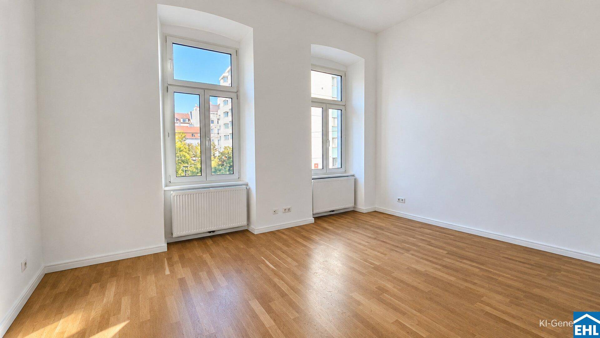 Lichtdurchfluteter Raum mit hellem Parkettboden und zwei hohen Fenstern.