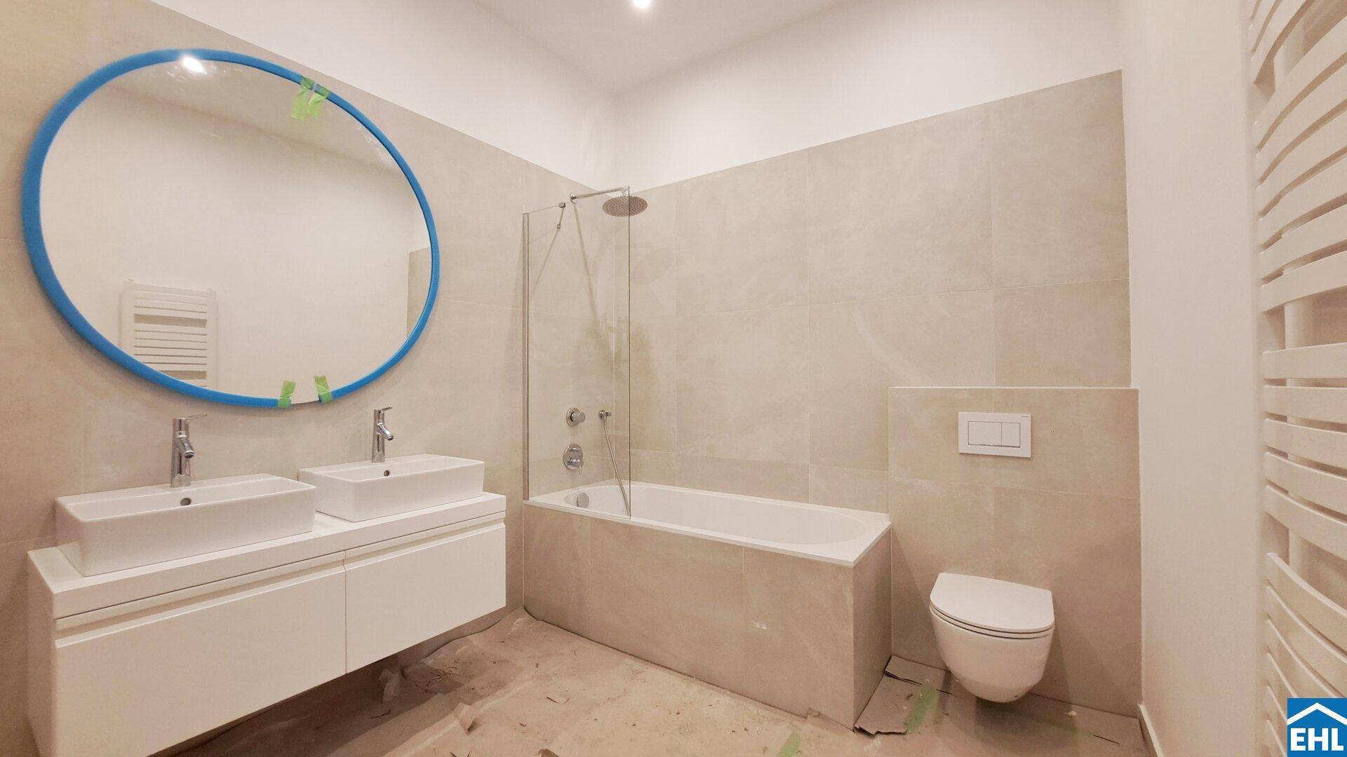 Modernes Badezimmer im Bau mit Doppelwaschbecken, Badewanne mit Dusche und Wand-WC.