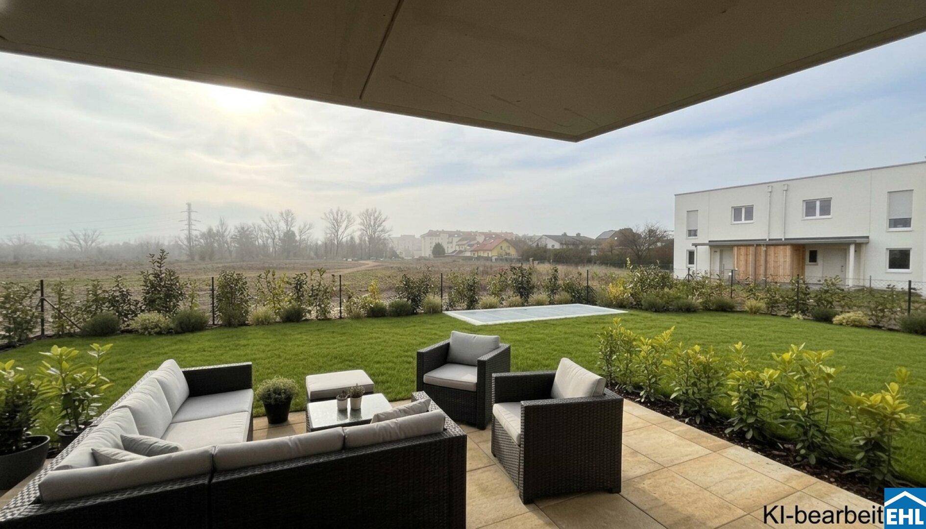 Möblierte Terrasse mit Garten, Rasenfläche und Blick ins Grüne vor einem modernen Neubau.
