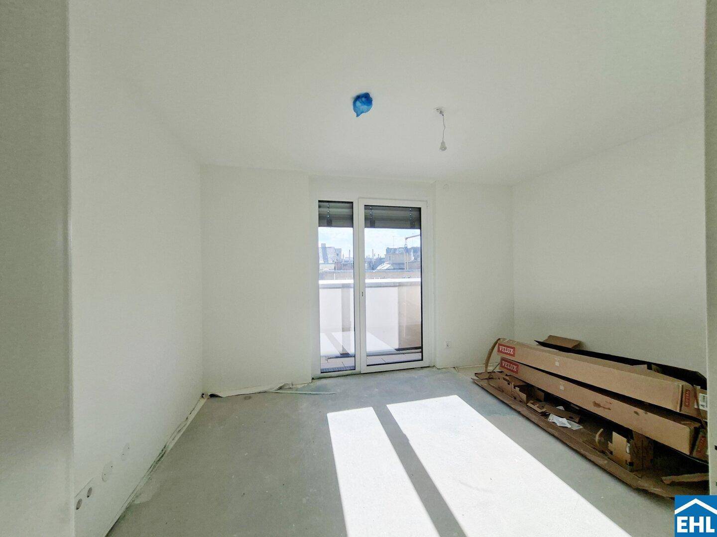 Leerer Raum im Rohbau mit Zugang zu einem Balkon und heller Atmosphäre.