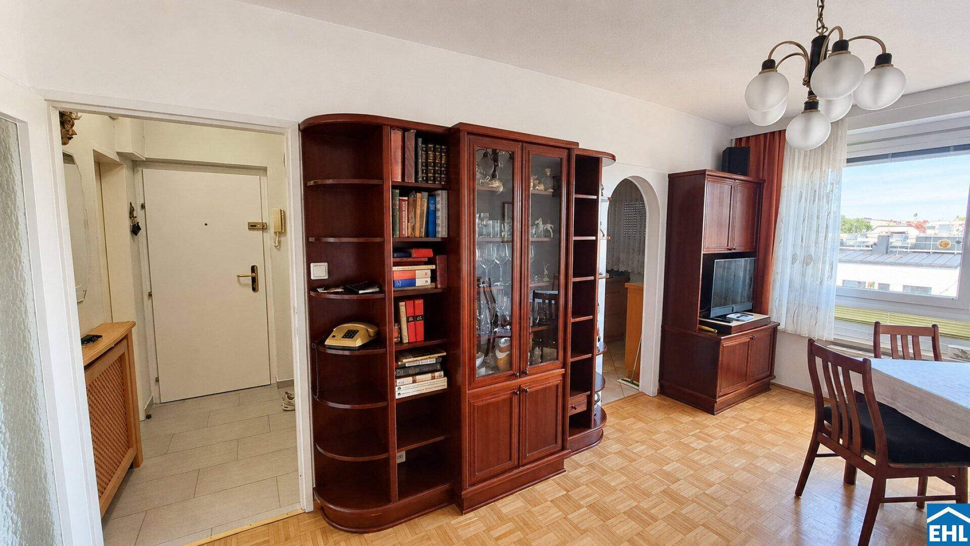 Geräumiger Wohnbereich mit großem Bücherregal und Zugang zum Flur, hell und einladend.