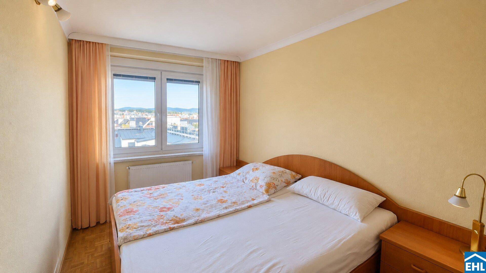 Gemütliches Schlafzimmer mit Einzelbett, Nachttisch und Fenster mit Blick auf die Stadt.