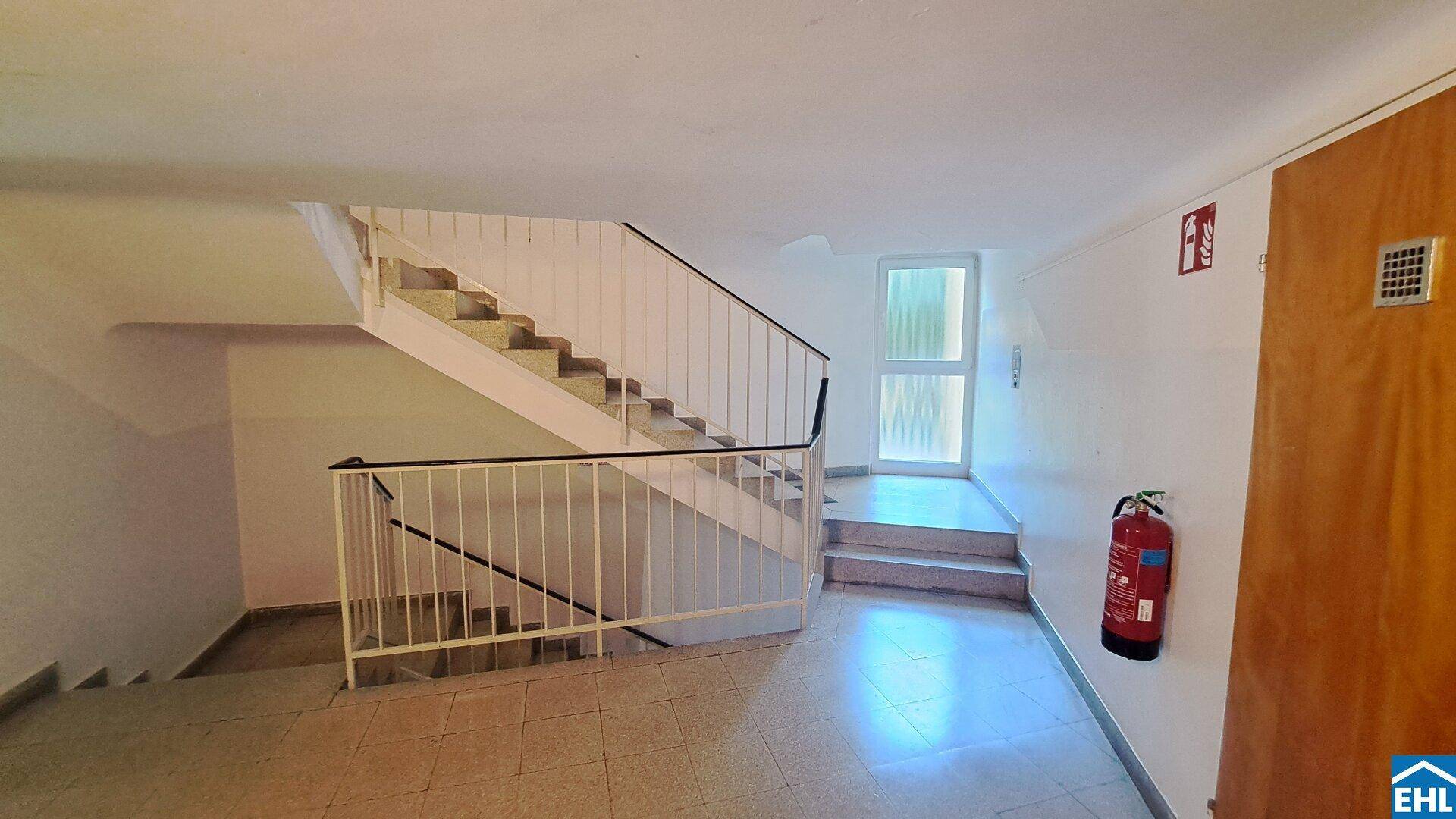 Heller Treppenaufgang in einem Wohngebäude mit robustem Geländer und Fliesenboden.