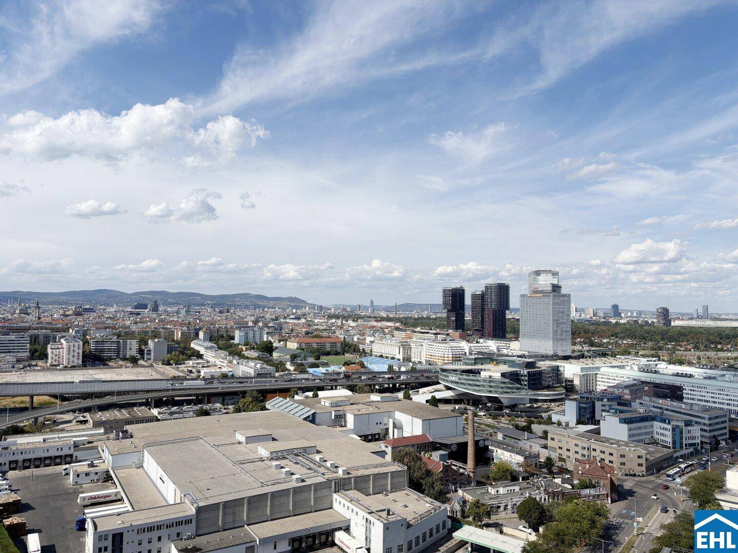 Panoramablick über die Stadt mit modernen Gebäuden und weitläufiger Infrastruktur unter blauem Himmel.