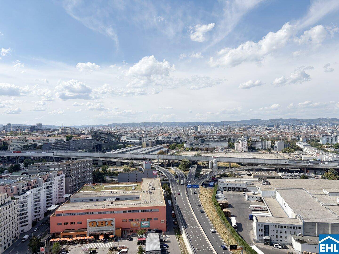 Weitläufiger Stadtblick mit Autobahnkreuz und Gewerbegebieten unter einem klaren Himmel.
