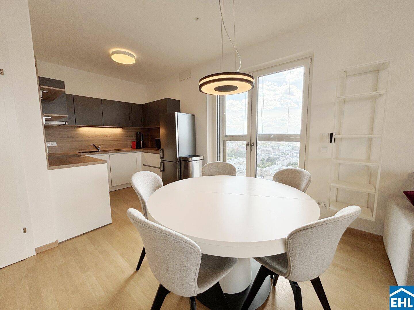 Moderner Essbereich mit rundem Tisch und offener Küche, hell und mit Stadtblick.
