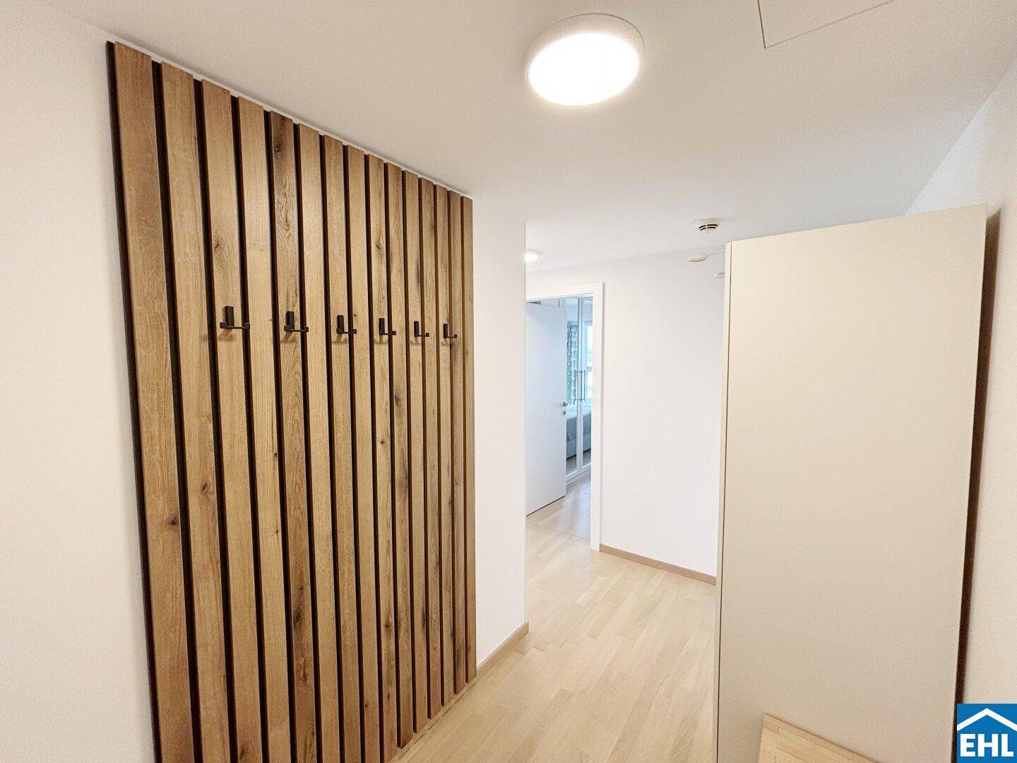 Moderner Flur mit Holzwandverkleidung und Garderobenhaken, die einen warmen Empfang bieten.