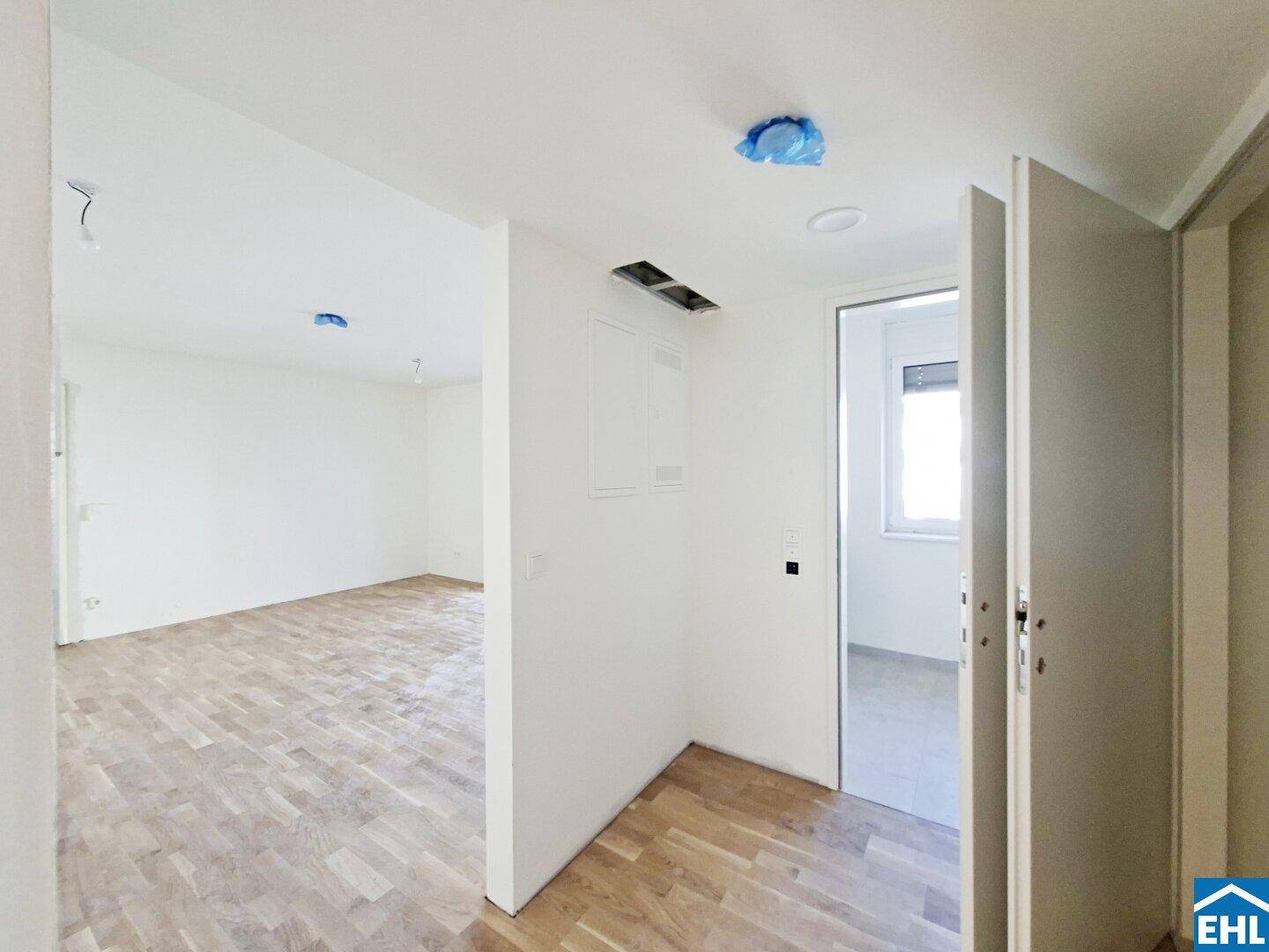 Heller Flur mit Parkettboden, der zu verschiedenen Räumen der Wohnung führt.