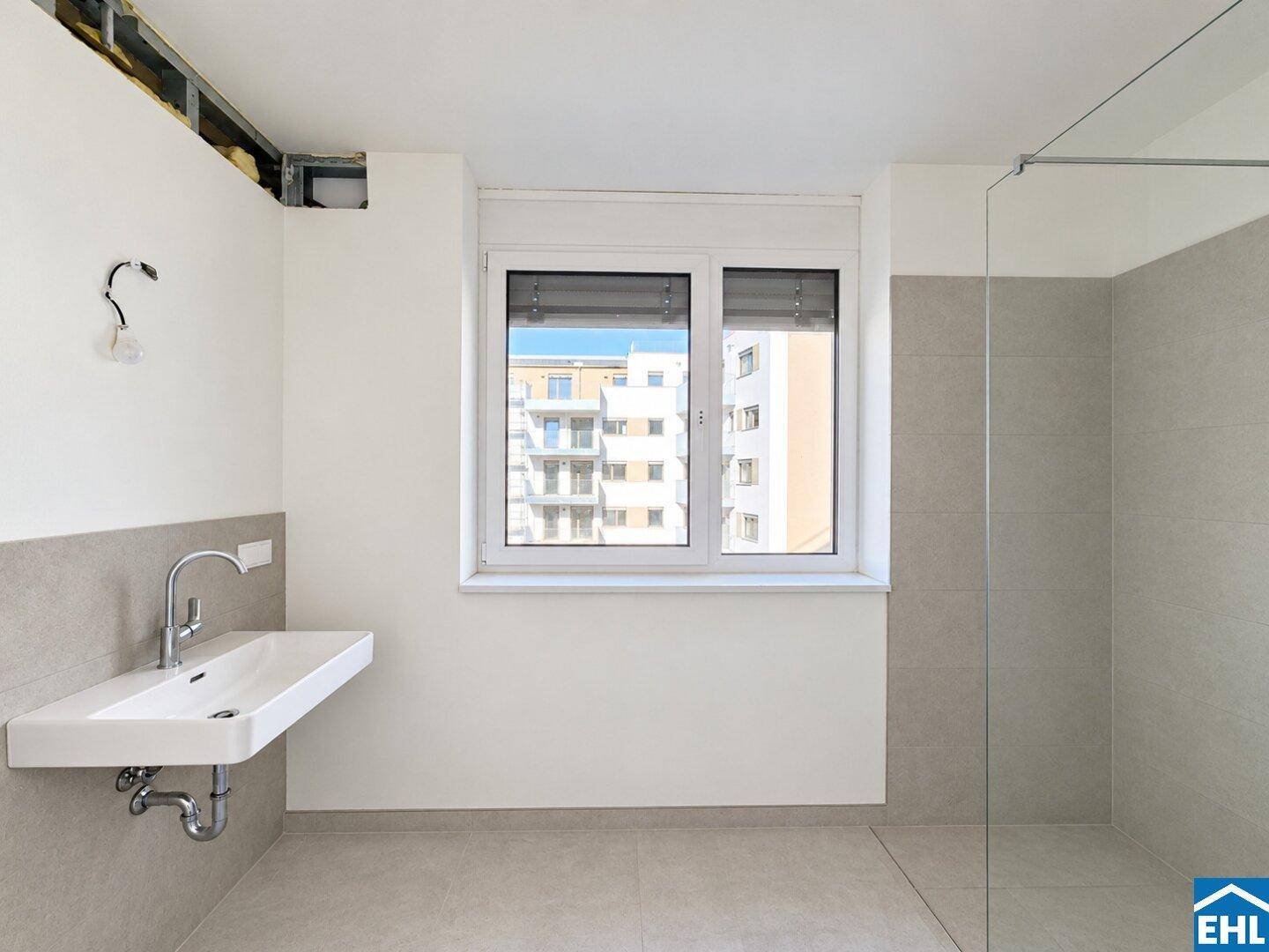 Modernes Badezimmer mit Waschtisch, begehbarer Dusche und Fenster für Tageslicht.
