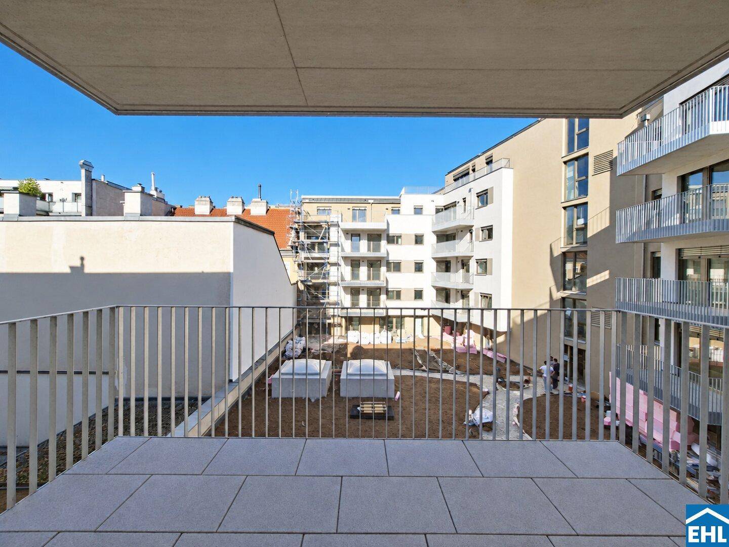 Balkon mit Fliesenboden und Blick auf den Innenhof und die umliegenden Gebäude.