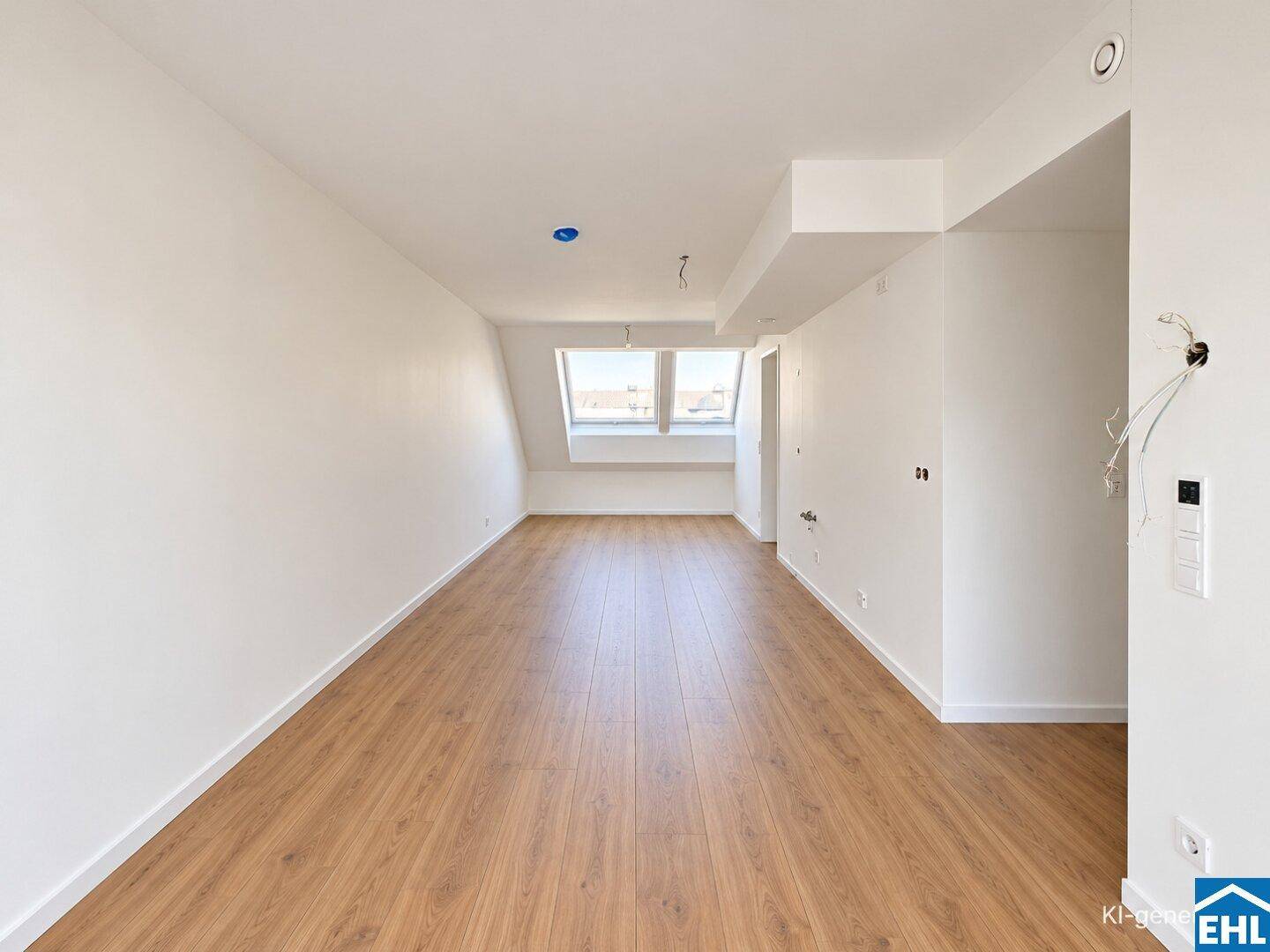 Leeres Dachzimmer mit schrägen Wänden, Laminatboden und einem großen Dachfenster.
