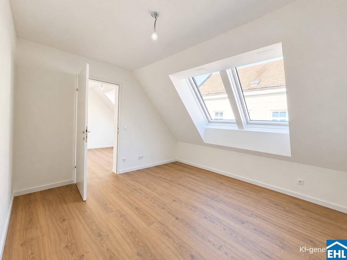 Helles Dachzimmer mit Laminatboden, schrägen Wänden und einem großen Dachfenster.
