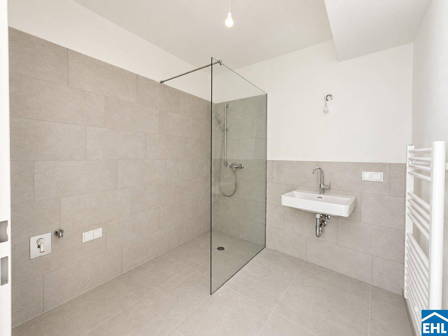 Modernes Badezimmer mit grauen Fliesen, begehbarer Dusche und beheiztem Handtuchhalter.