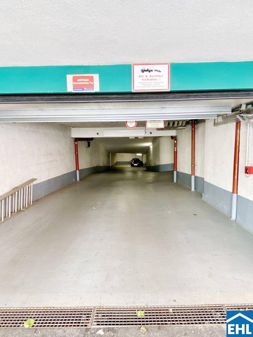 Einfahrt zu einer Tiefgarage mit Betonboden und Beleuchtung.