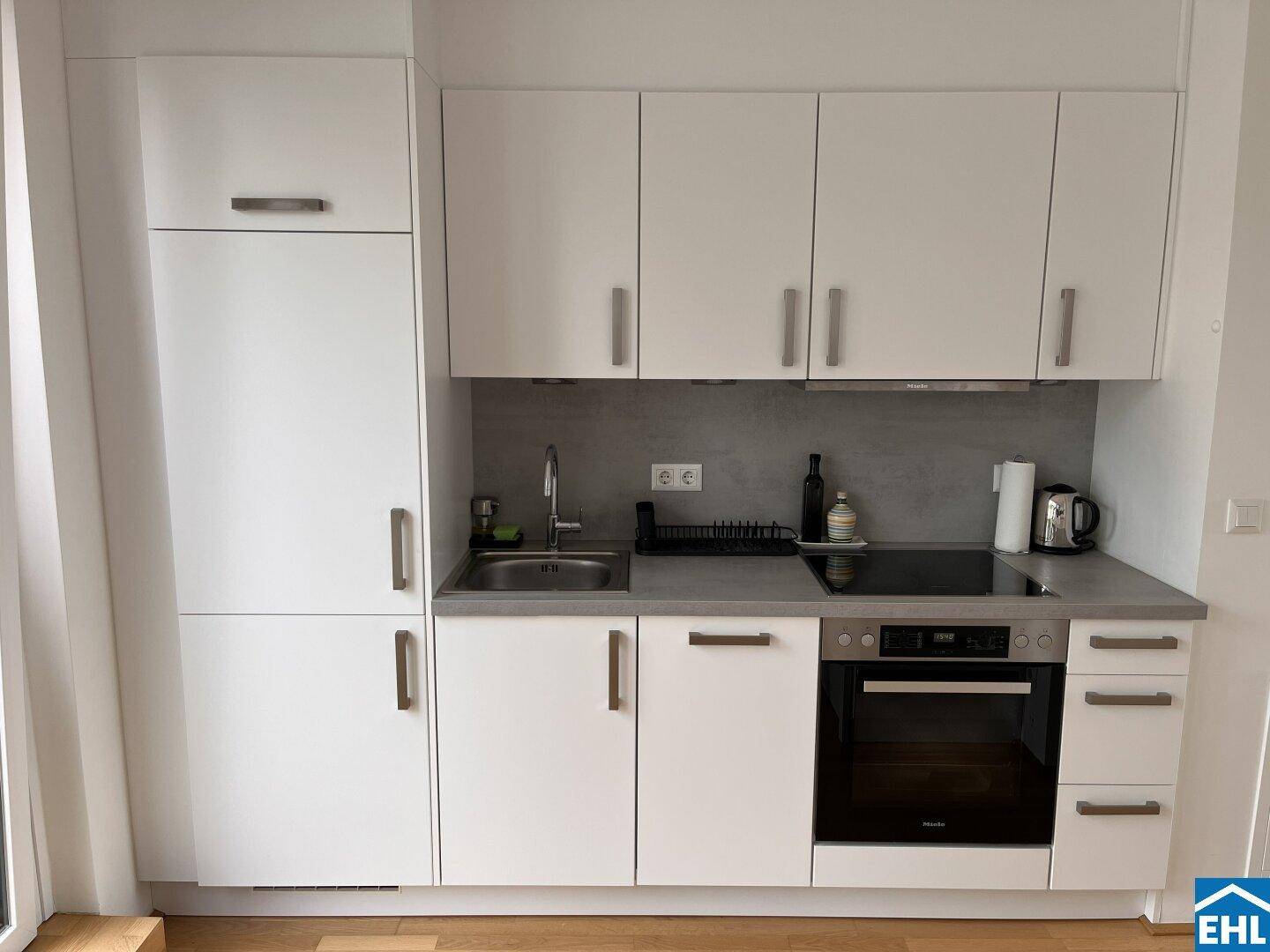 Detailansicht der modernen Küchenzeile mit weißen Fronten, integriertem Backofen und Kochfeld.