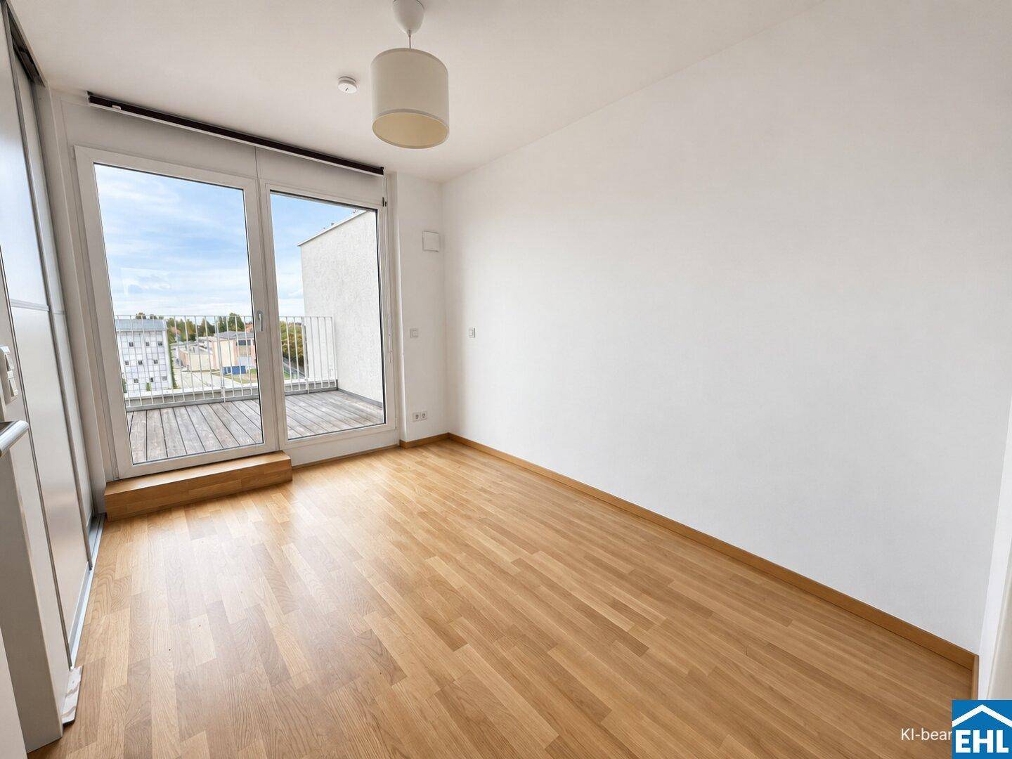 Leeres Schlafzimmer mit Holzboden, weißen Wänden und direktem Zugang zu einem Balkon oder einer Terrasse.