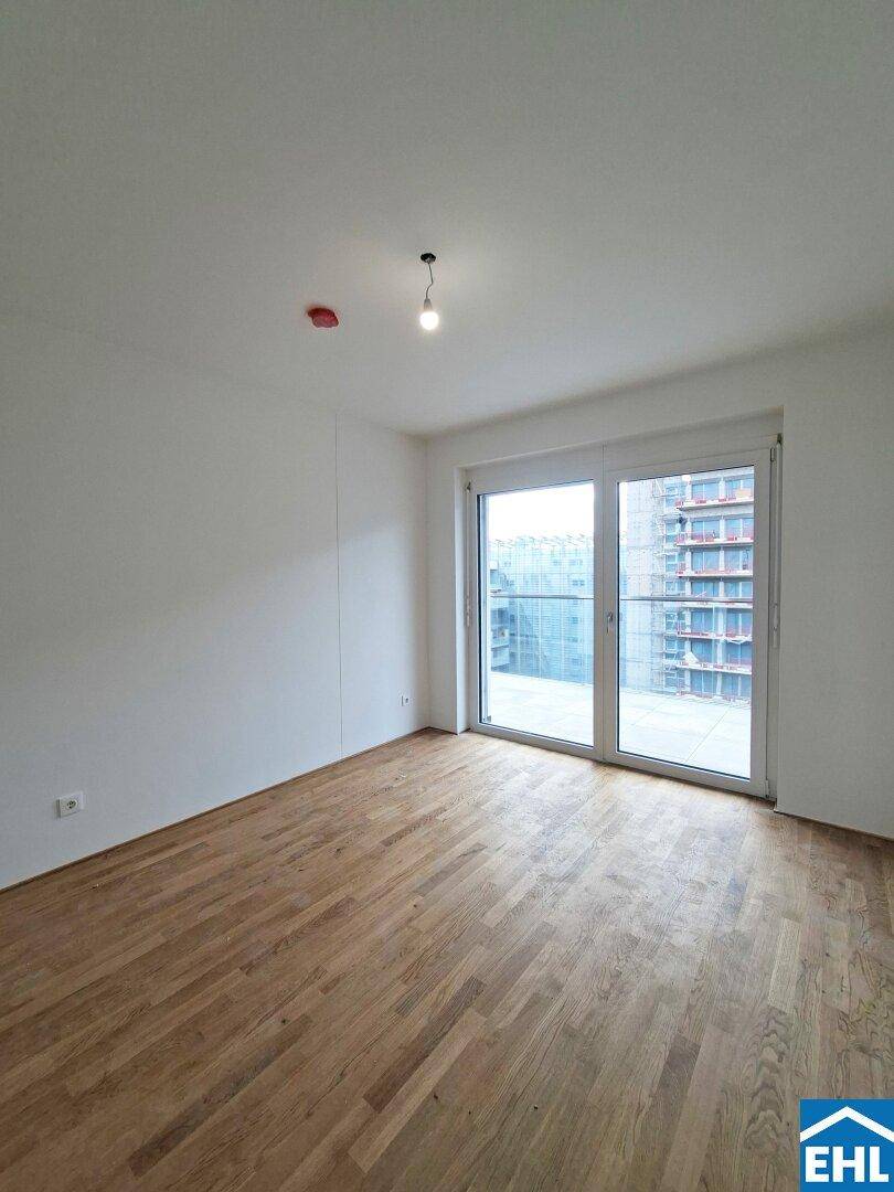 Helles Schlafzimmer mit Parkettboden und großem Schiebefenster zum Außenbereich.