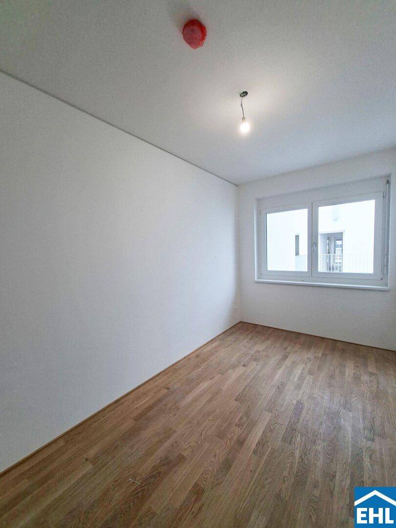 Gemütliches Zimmer mit Parkettboden und weiß gestrichenen Wänden, ideal als Schlafzimmer.