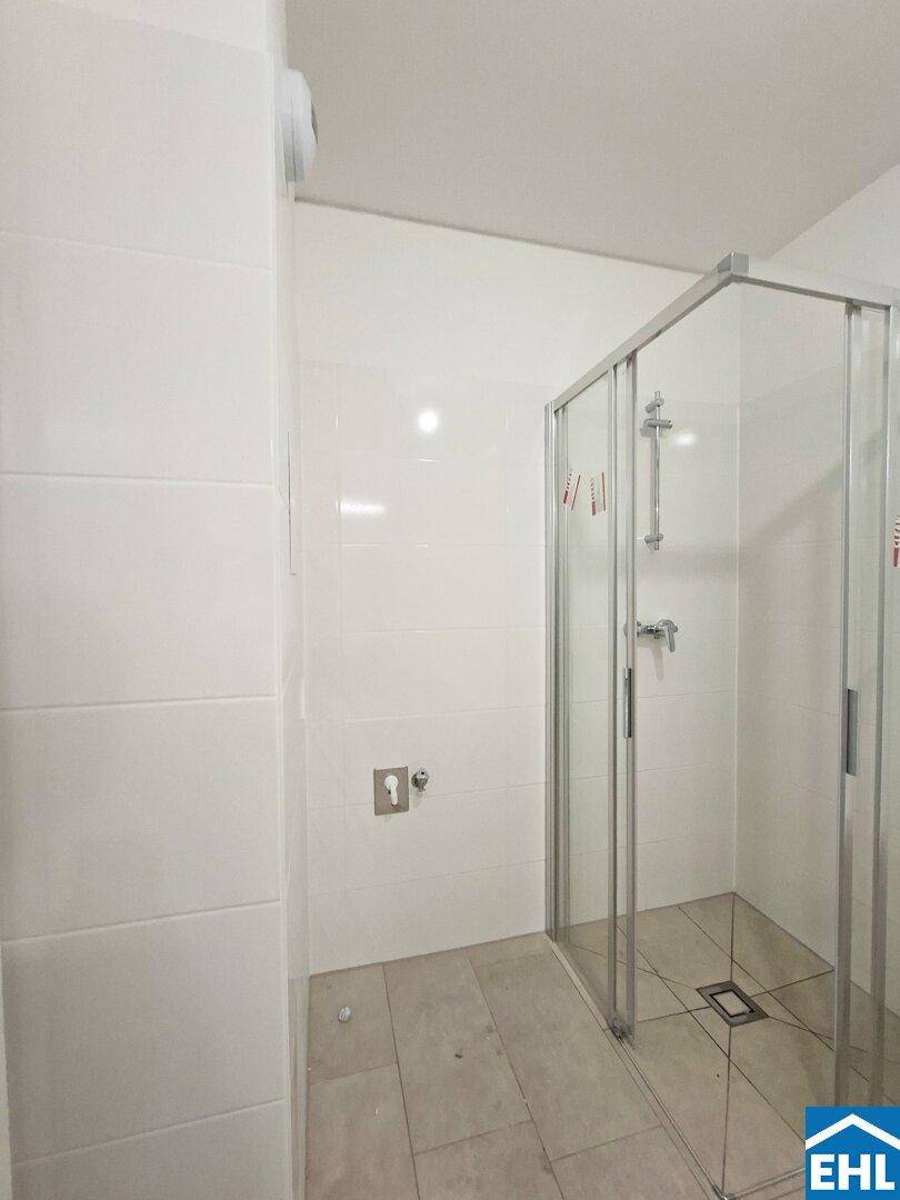 Modernes Badezimmer mit weißen Fliesen und einer geräumigen Glasduschkabine.