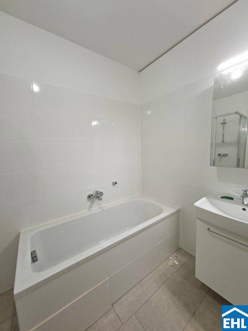 Helles Badezimmer mit Badewanne, Einzelwaschbecken und Spiegelschrank.