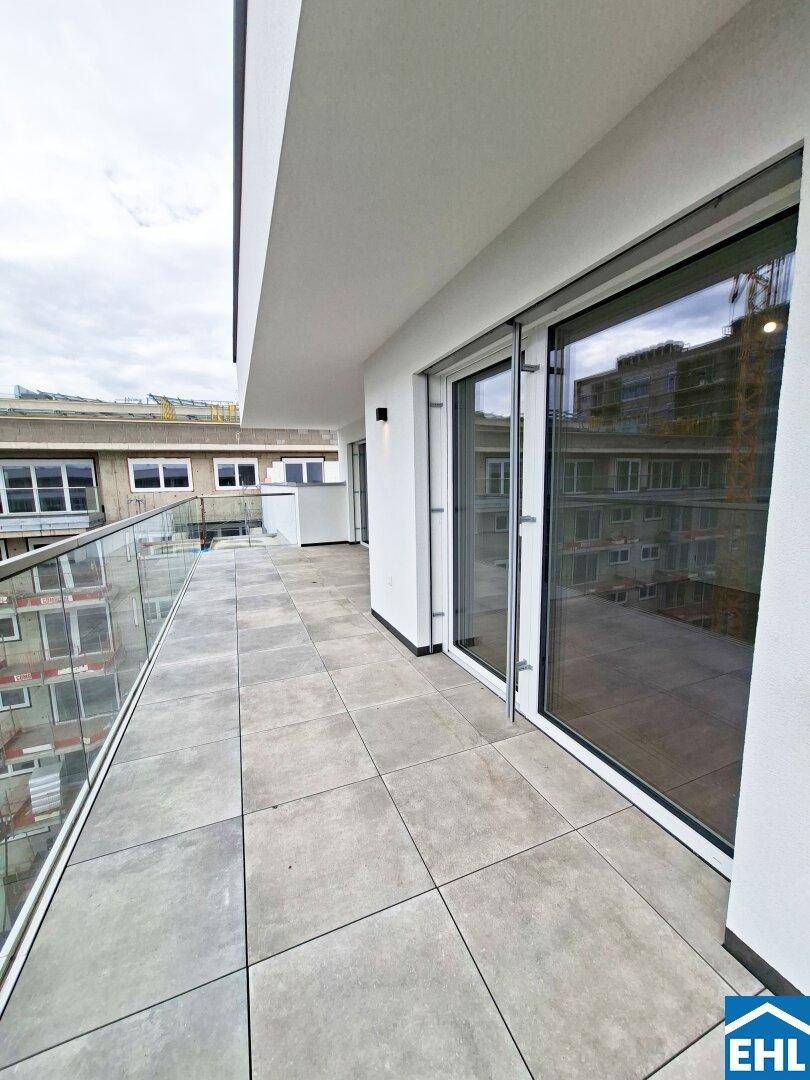 Geräumiger Balkon mit Fliesenboden und Glasgeländer, bietet Platz für Outdoor-Möbel.