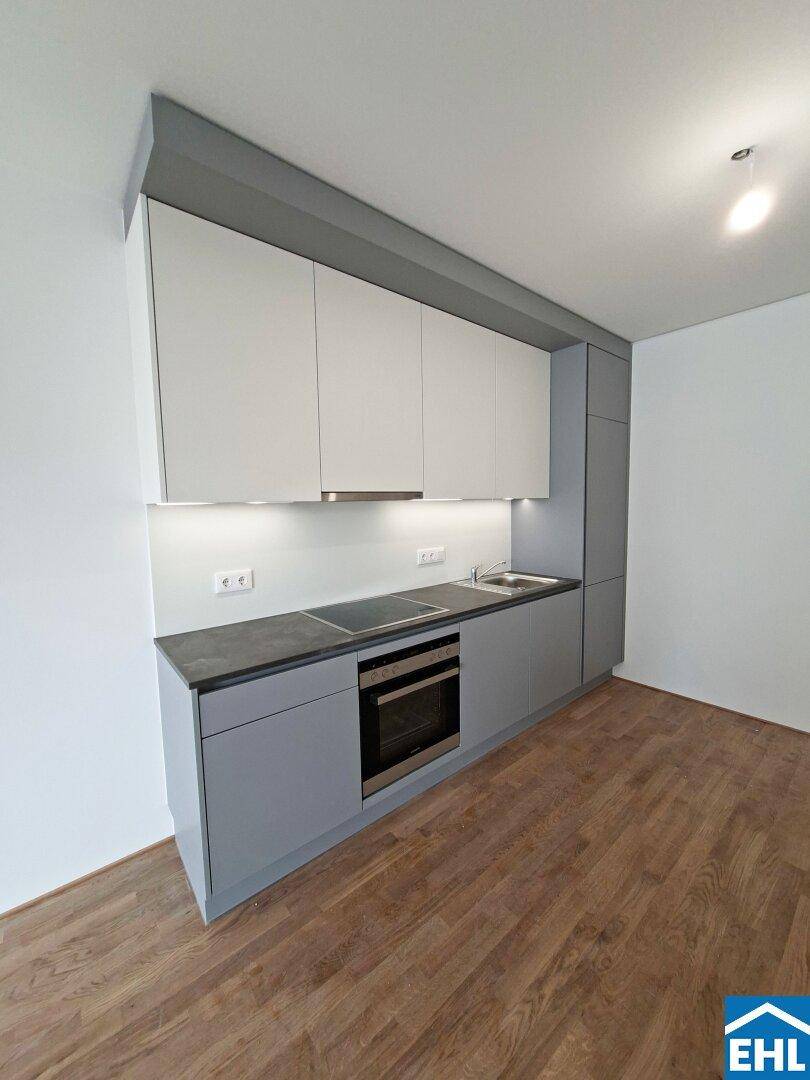 Moderne Einbauküche mit grauen Unterschränken, weißen Oberschränken und integrierten Geräten.