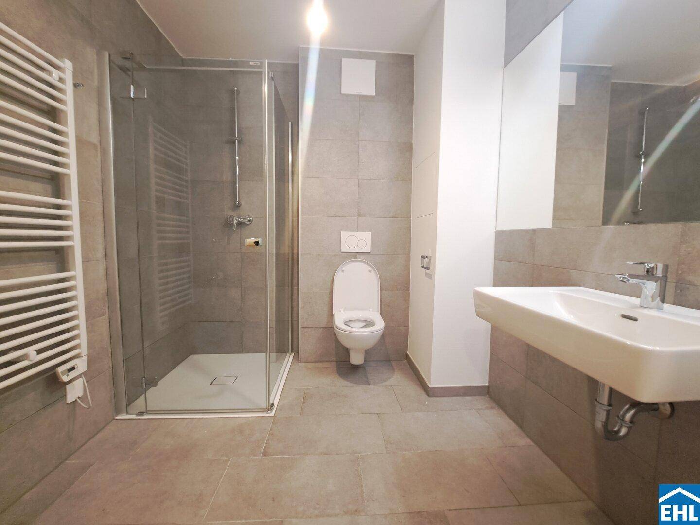 Modernes Badezimmer mit Duschkabine, Wand-WC, Waschbecken und beheiztem Handtuchhalter.