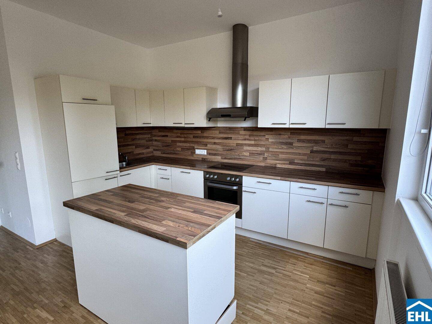 Moderne Einbauküche mit weißen Fronten, Holzoptik-Arbeitsplatten und praktischer Kochinsel.