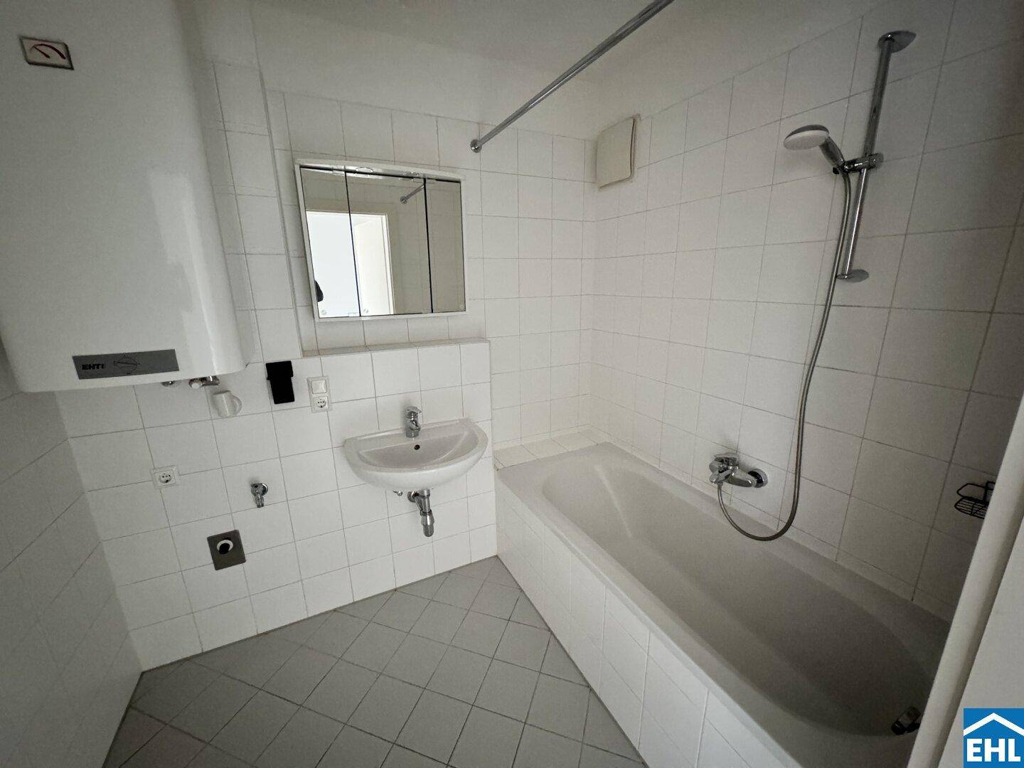 Funktionales Badezimmer mit Badewanne, Waschbecken und weißen Fliesen.