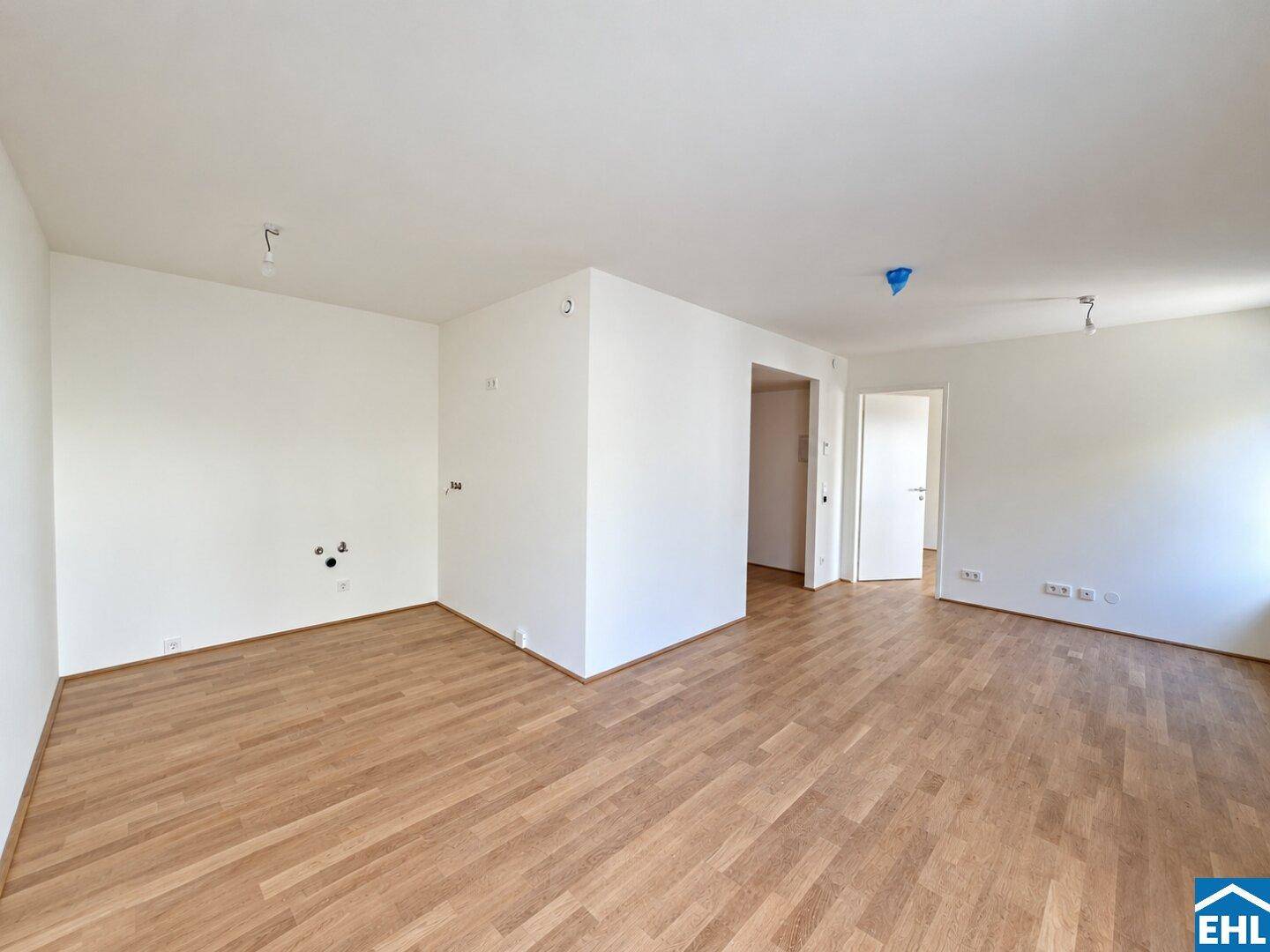 Unmöblierte Küche mit Parkettboden und Anschlüssen für die Kücheninstallation.