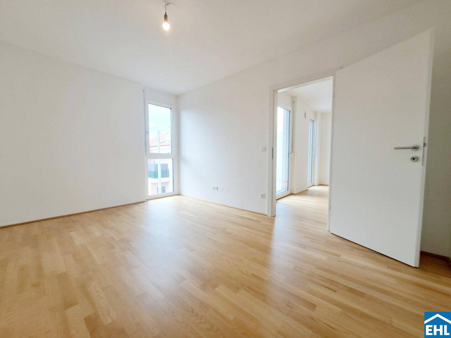 Helles Schlafzimmer mit Parkettboden und großem Fenster, bietet eine angenehme Wohnatmosphäre.