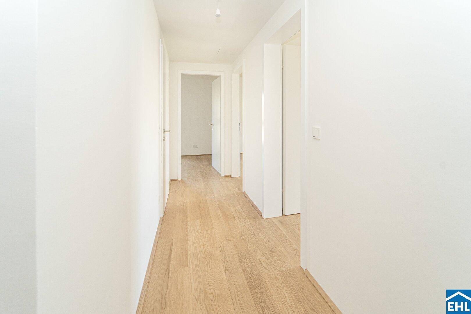 Heller Flur mit Holzboden und mehreren Türen zu angrenzenden Räumen, gut beleuchtet.