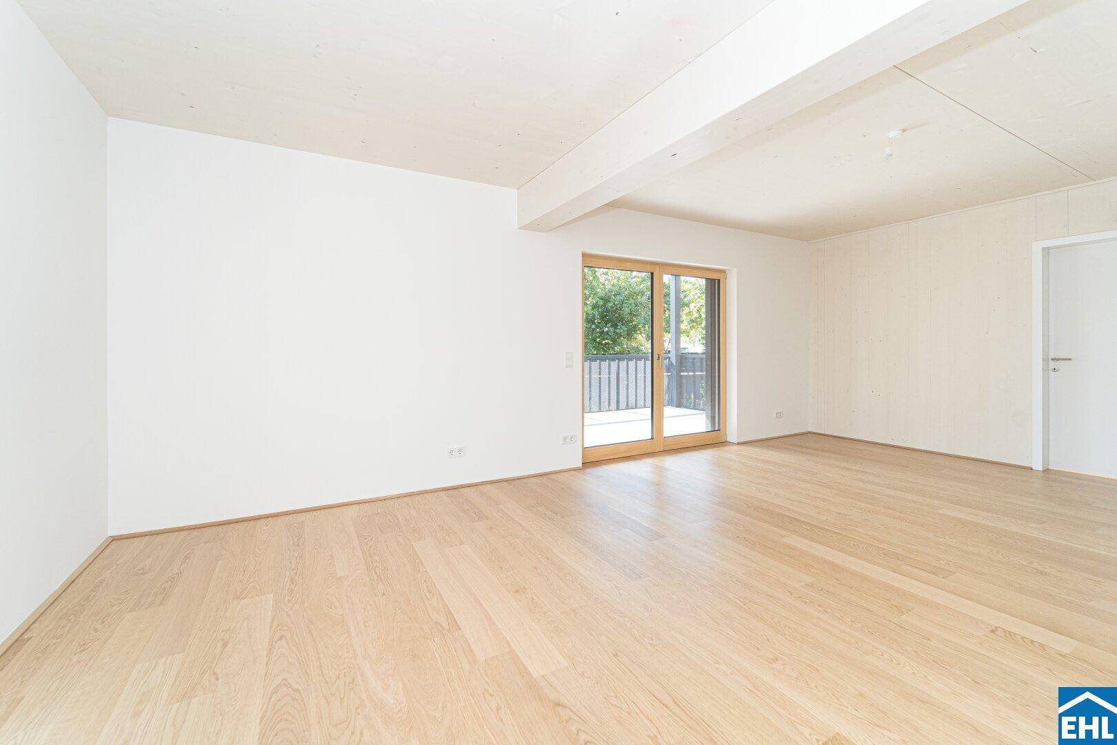 Leeres Zimmer mit Holzboden und Schiebetür zum Außenbereich, bietet direkten Balkonzugang.